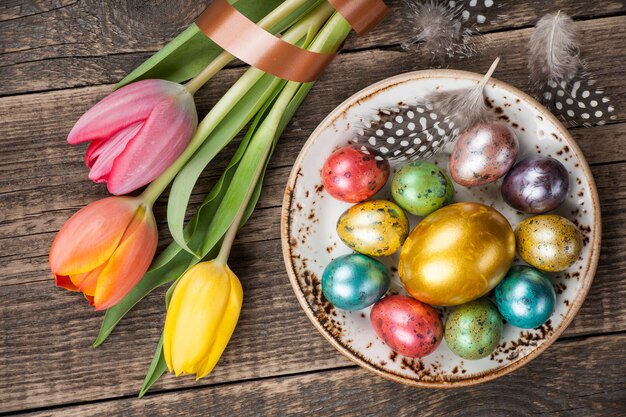 Uova di Pasqua e tulipani su fondo di legno