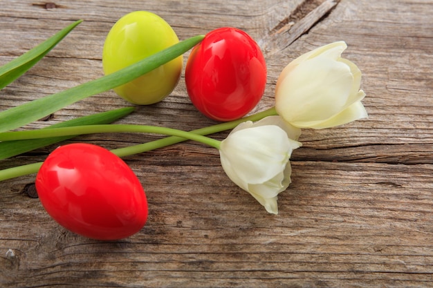 Uova di Pasqua e tulipani su fondo di legno