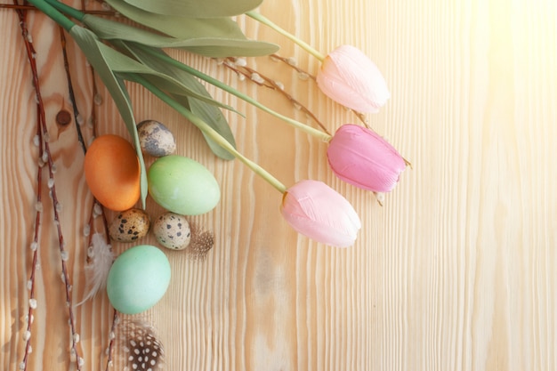 Uova di Pasqua e tulipani su una tavola di legno. Luce del mattino.