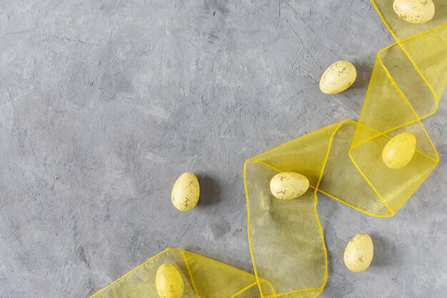 Uova di Pasqua gialle con nastro giallo su sfondo grigio vista dall'alto