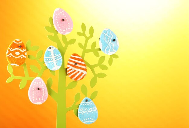 Uova di Pasqua in feltro su albero decorativo su sfondo colorato
