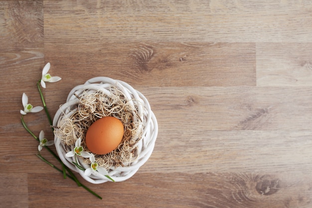 Uova di Pasqua In nido sulla tavola rustica di legno, fondo di festa per la vostra decorazione. Concetto di festa di Pasqua e della primavera con lo spazio della copia.