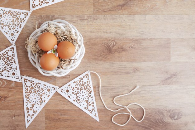 Uova di Pasqua In nido sulla tavola rustica di legno, fondo di festa per la vostra decorazione. Concetto di festa di Pasqua e della primavera con lo spazio della copia.