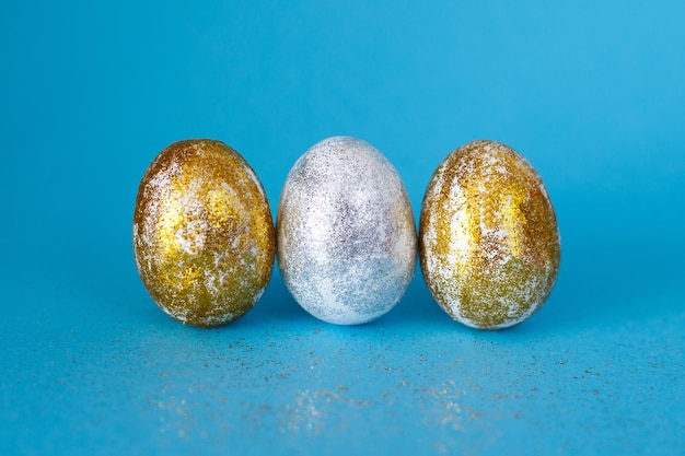 Uova di Pasqua in oro e argento su sfondo blu Concetto di Pasqua Buona Pasqua Spazio di copia