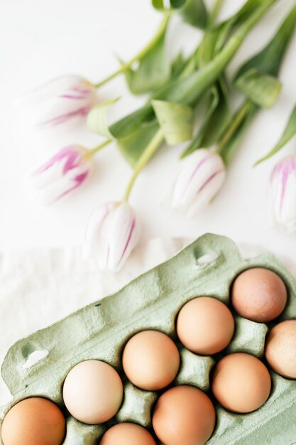 Uova di Pasqua in un cartone verde e tulipani flatlay