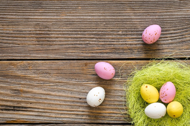 Uova di Pasqua in un nido decorativo su una vista superiore del fondo di legno