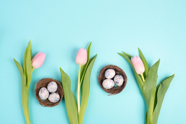 Uova di Pasqua in un nido di uccelli, tulipani rosa, biglietto di auguri per le vacanze, sfondo della stagione primaverile