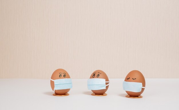 uova di pasqua in una maschera medica per decorare le vacanze di pasqua su uno sfondo di pesca con copyspace