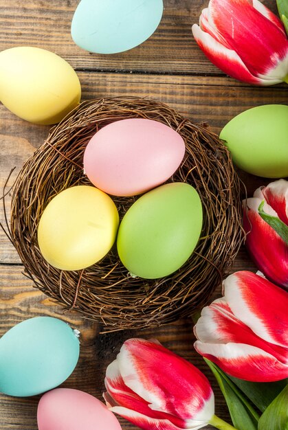 Uova di Pasqua multicolori con i fiori dei tulipani su fondo di legno,