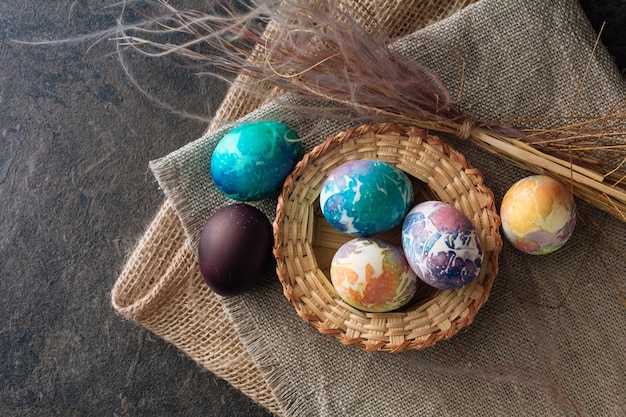 Uova di Pasqua multicolori di toni blu su uno sfondo di panno marrone. Vista dall'alto