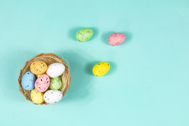 Uova di Pasqua multicolori in un nido su sfondo blu con spazio per scritte di testo Base per una cartolina Vista dall'alto