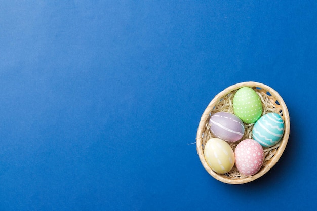 Uova di Pasqua multicolori nel cesto intrecciato su sfondo colorato Concetto di vacanza delle uova di Pasqua di colore pastello con spazio per la copia