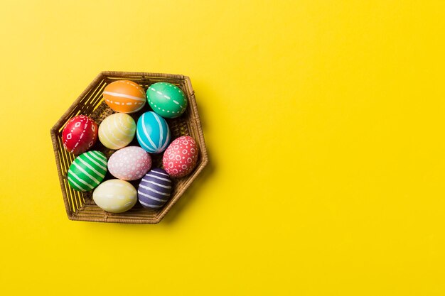 Uova di Pasqua multicolori nel cesto intrecciato su sfondo colorato Concetto di vacanza delle uova di Pasqua di colore pastello con spazio per la copia