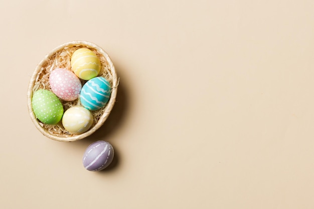 Uova di Pasqua multicolori nel cesto intrecciato su sfondo colorato Concetto di vacanza delle uova di Pasqua di colore pastello con spazio per la copia