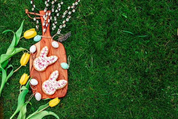 Uova di Pasqua su una tavola di legno con un biscotto a forma di coniglietto in cima