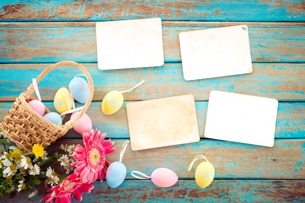 Uova di Pasqua variopinte in nido con il fiore e vecchio album di foto di carta vuoto sulla tavola di legno