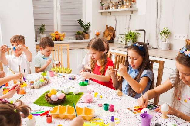 Uova di pittura per bambini felici. Amici che si preparano per la Pasqua. Concetto di lavoro di squadra