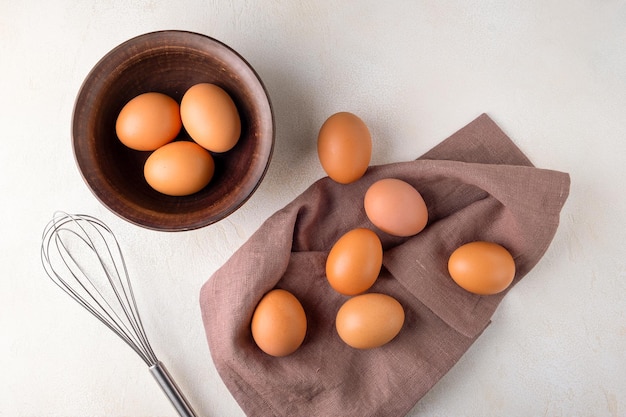 Uova di pollo in una ciotola su un tavolo con una frusta per battere le uova