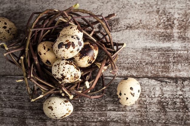 Uova di quaglia in un nido su un fondo di legno rustico. Concetto di cibo sano