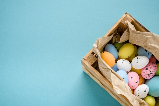 Uova dipinte in una scatola di legno su sfondo blu Copia spazio per il testo Carta di Pasqua