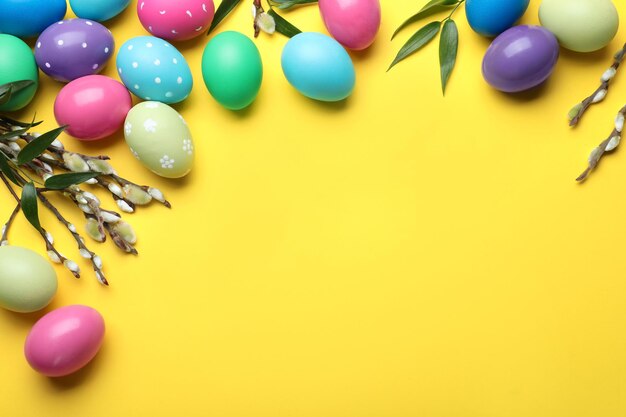 Uova dipinte luminose e salici purulenti su sfondo giallo piatto con spazio per il testo Buona Pasqua
