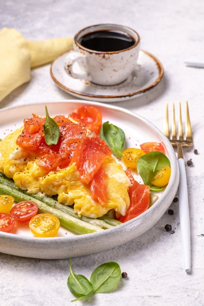 Uova fritte con asparagi verdi e salmone, pomodorini e spinaci freschi.