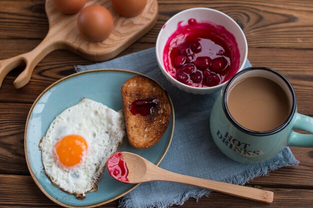 uova fritte con pane tostato bianco e marmellata di ciliegie Colazione con una tazza di caffè profumato