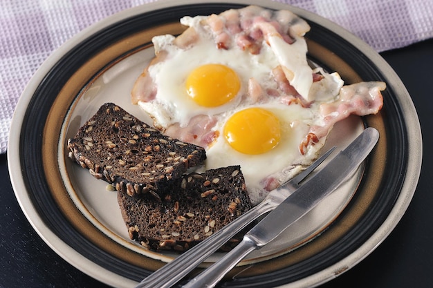 Uova fritte con tuorlo intero, pancetta e pane tostato