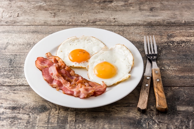 Uova fritte e pancetta affumicata per la prima colazione sulla tavola di legno