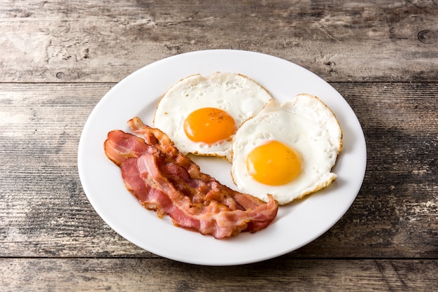 Uova fritte e pancetta affumicata per la prima colazione sulla tavola di legno