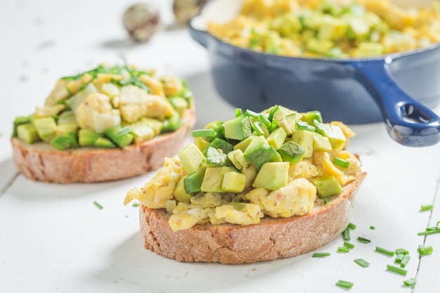 Uova fritte fatte in casa con erba cipollina e avocado su tavola bianca