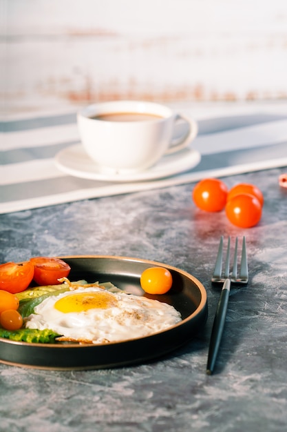 Uova fritte in padella con pomodorini e caffè a colazione