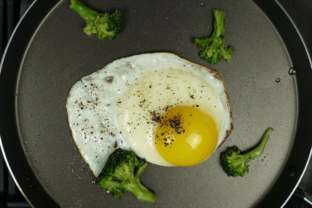 Uova fritte in padella cosparse di spezie e sale con broccoli