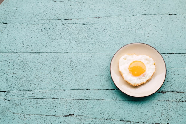 Uova fritte, pane tostato, caffè, set da colazione posto su un tavolo di legno blu