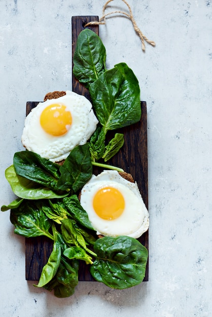 Uova fritte per la colazione con spinaci freschi