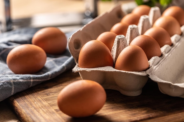 Uova in una scatola di cartone su una tavola di legno in cucina.