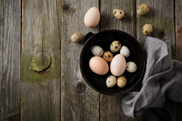 Uova intere di quaglia e gallina in una piccola padella di ghisa