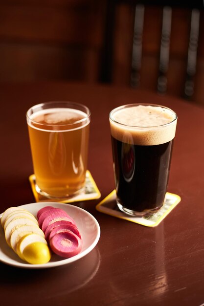 Uova marinate in salamoia rosa e gialle su un piatto bianco e un bicchiere di birra nel pub