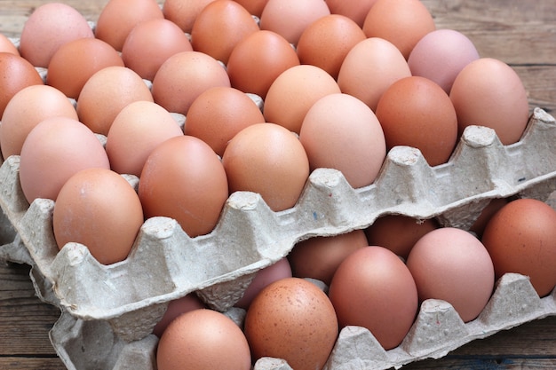 Uova marroni fresche del pollo nell&#39;imballaggio su un pavimento del legname
