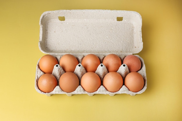 Uova marroni in imballaggi ecologici realizzati con materiali riciclati su uno sfondo giallo chiaro isolato