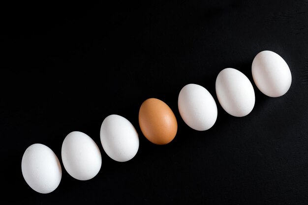 Uova nella linea Uova di gallina Uova bianche su sfondo nero Foto verticale Sfondo di uova