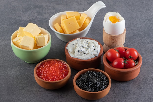 Uova sode, formaggio e caviale per una sana colazione sul tavolo di pietra.