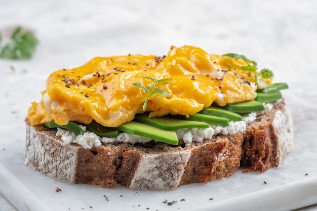 Uova strapazzate con avocado e crema di formaggio su pane tostato