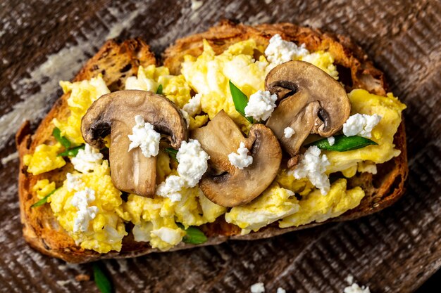 Uova strapazzate con cipolla verde su pane croccante integrale di grano segale, colazione o brunch salutare fatto in casa. Pasto fatto in casa, vista dall'alto.