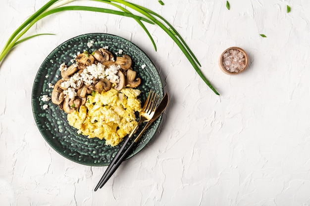 Uova strapazzate con funghi champignon. Deliziosa colazione o spuntino su un tavolo luminoso.