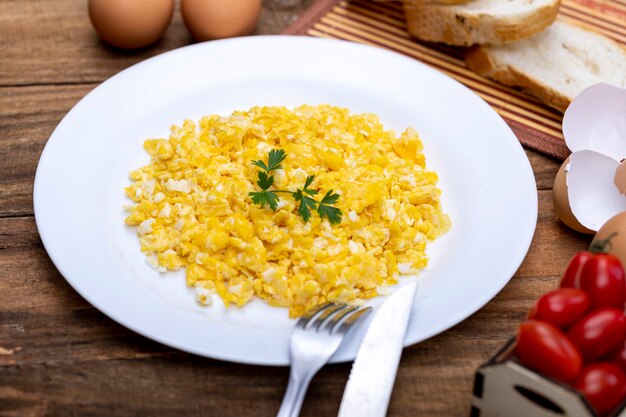 Uova strapazzate fresche sul piatto bianco sul tavolo della colazione