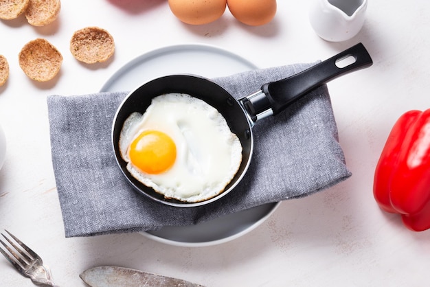 Uova strapazzate, friggere da un uovo in una piccola padella sul tavolo della cucina