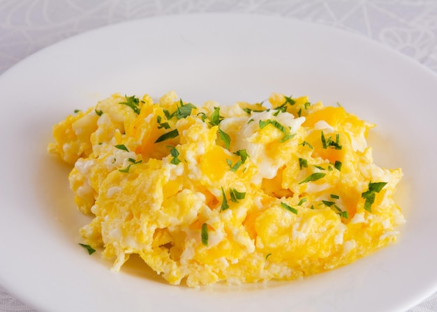 Uova strapazzate su fondo bianco del primo piano dell'alimento della prima colazione del piatto