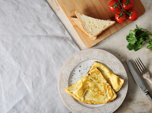 Uova strapazzate su un tovagliolo piatto, prezzemolo, pomodori, toast e tessile
