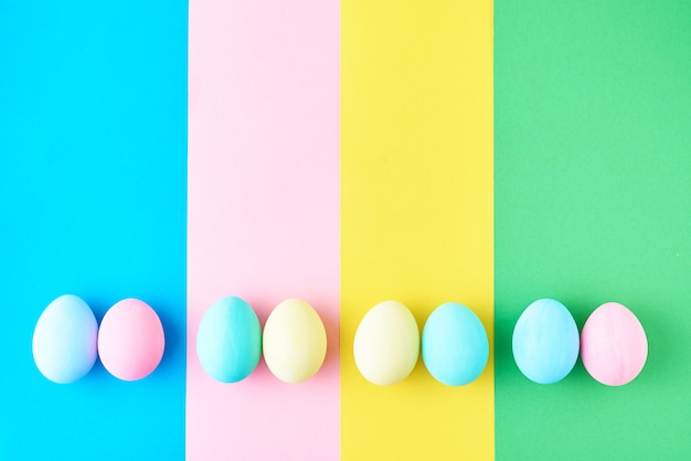Uova su fondo a strisce colorato, vista superiore, concetto di minimalismo